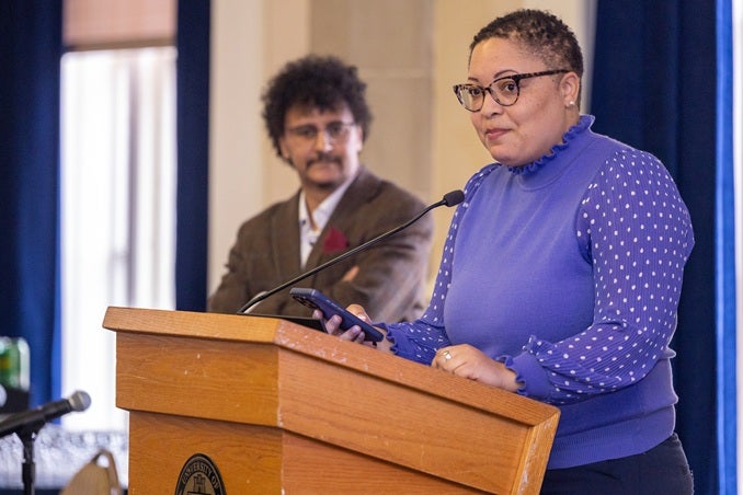 A speaker stands at a podium talking into a microphone.