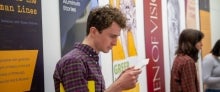 Students at an exhibit, main student in frame is reading a paper