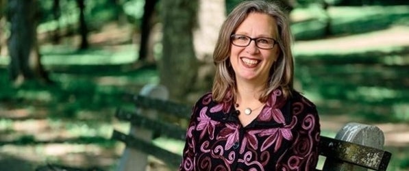 Smiling woman sitting on a park bench outside