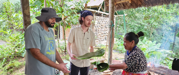 Eulodia Dagua teaching two Pitt students, Pranav Rajupalepu (left) and Liam Weixel (right) how to wrap fish for cooking 