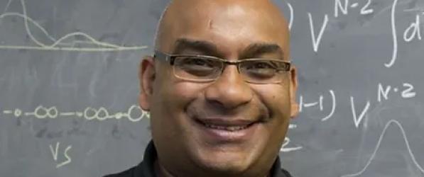 man smiling in front of a blackboard