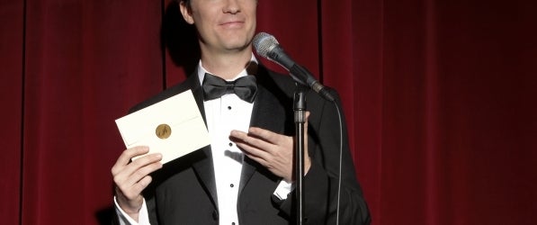 man in tuxedo with award envelope